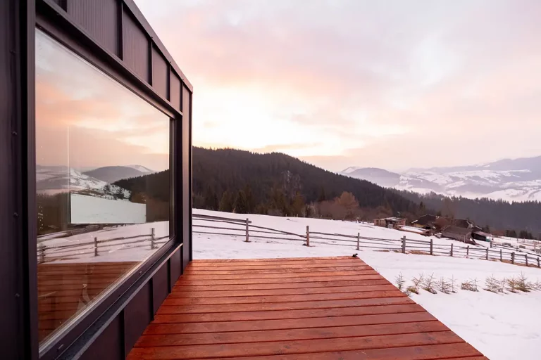 Haus mit Holz-Terrasse in mit Schnee bedeckter Natur-Landschaft