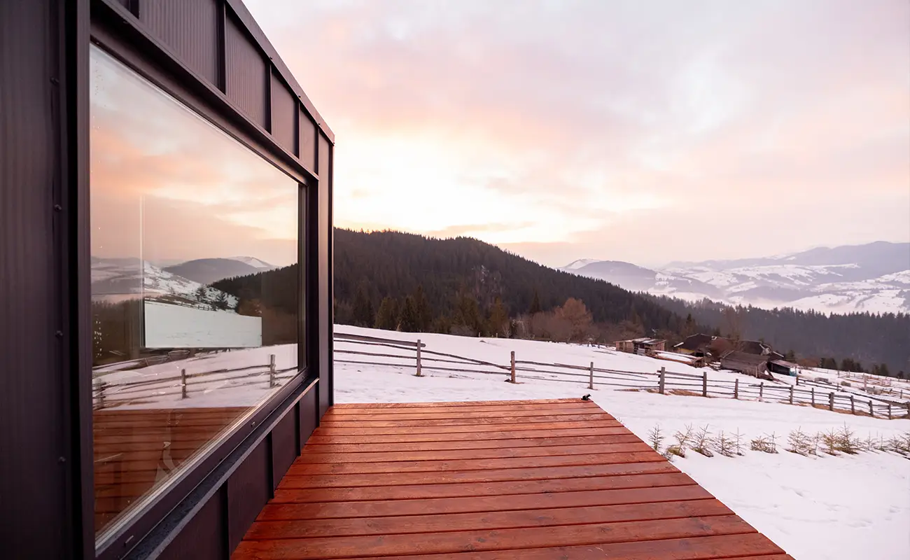 Haus mit Holz-Terrasse in mit Schnee bedeckter Natur-Landschaft