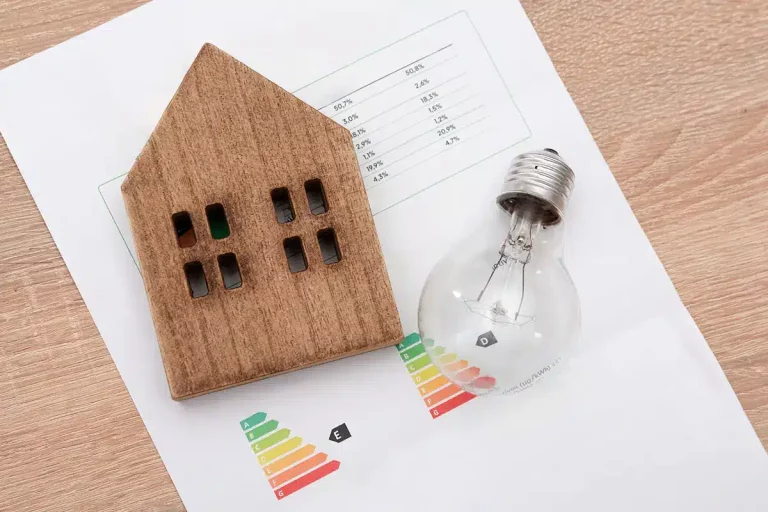 Holzhausmodell und Glühbirne auf Energieeffizienz-Bewertungstabelle