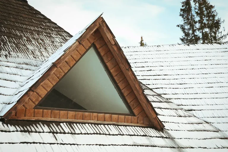 Dachfenster eines Holzhauses mit Schnee