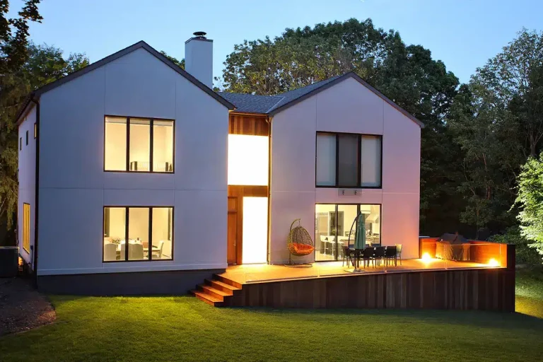 Zeitgenössisches Wohnhaus mit Holzterrasse und Garten im Abendlicht