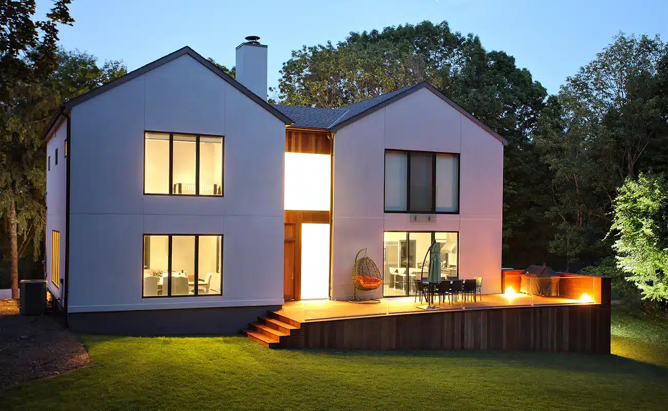 Zeitgenössisches Wohnhaus mit Holzterrasse und Garten im Abendlicht