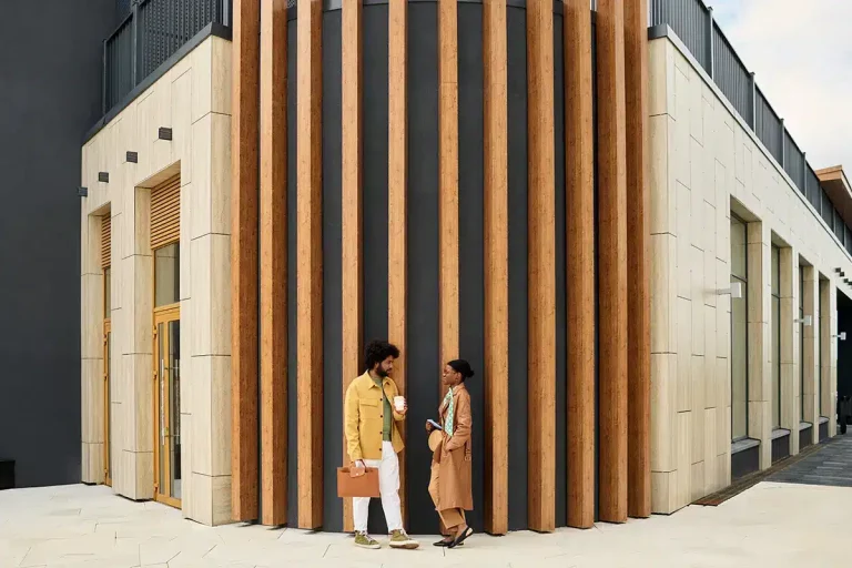 Zwei Personen unterhalten sich vor einem modernen Gebäude mit Holzlamellen