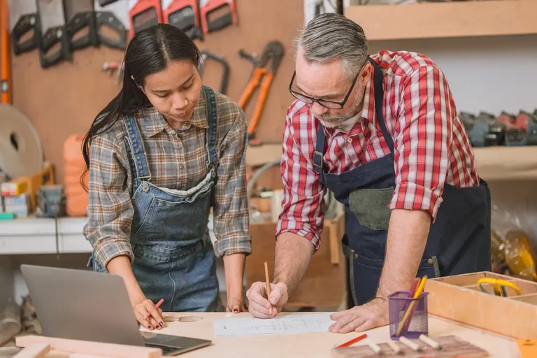 Handwerkerteam bei der Arbeit an Entwürfen in einer gut ausgestatteten Werkstatt