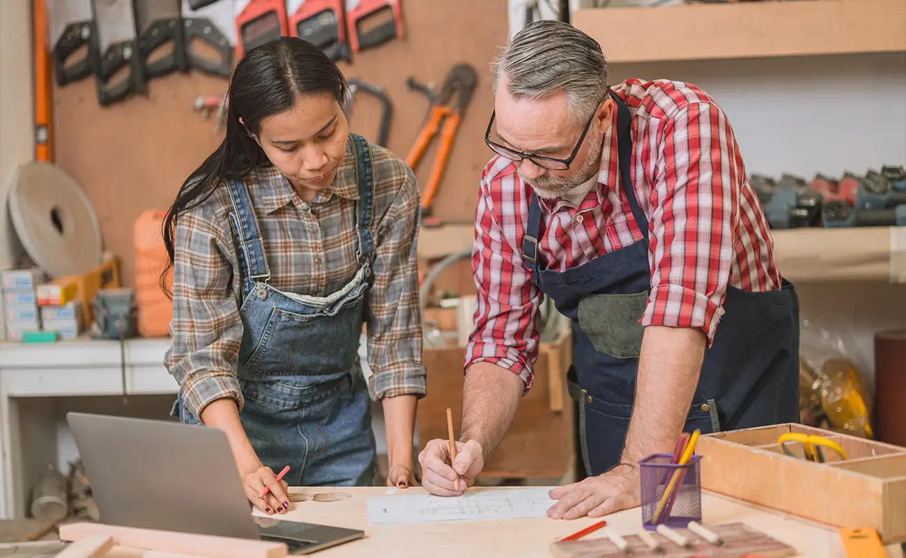 Handwerkerteam bei der Arbeit an Entwürfen in einer gut ausgestatteten Werkstatt