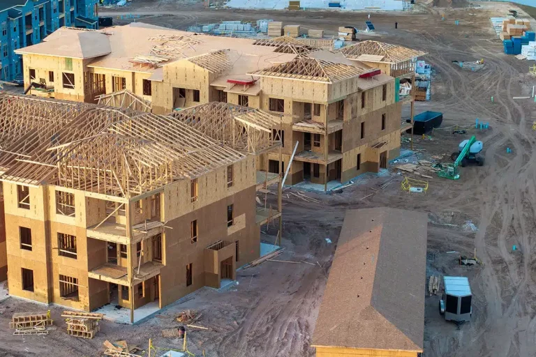 Baustelle mit mehreren mehrstöckigen Gebäuden aus Holz im frühen Bauzustand.